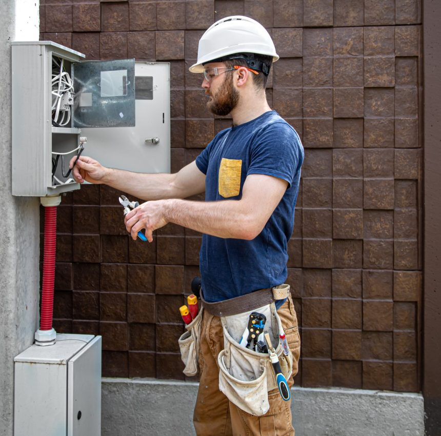 electrician-builder-work-examines-cable-connection-electrical-line-fuselage-industrial-switchboard-professional-overalls-with-electrician-s-tool