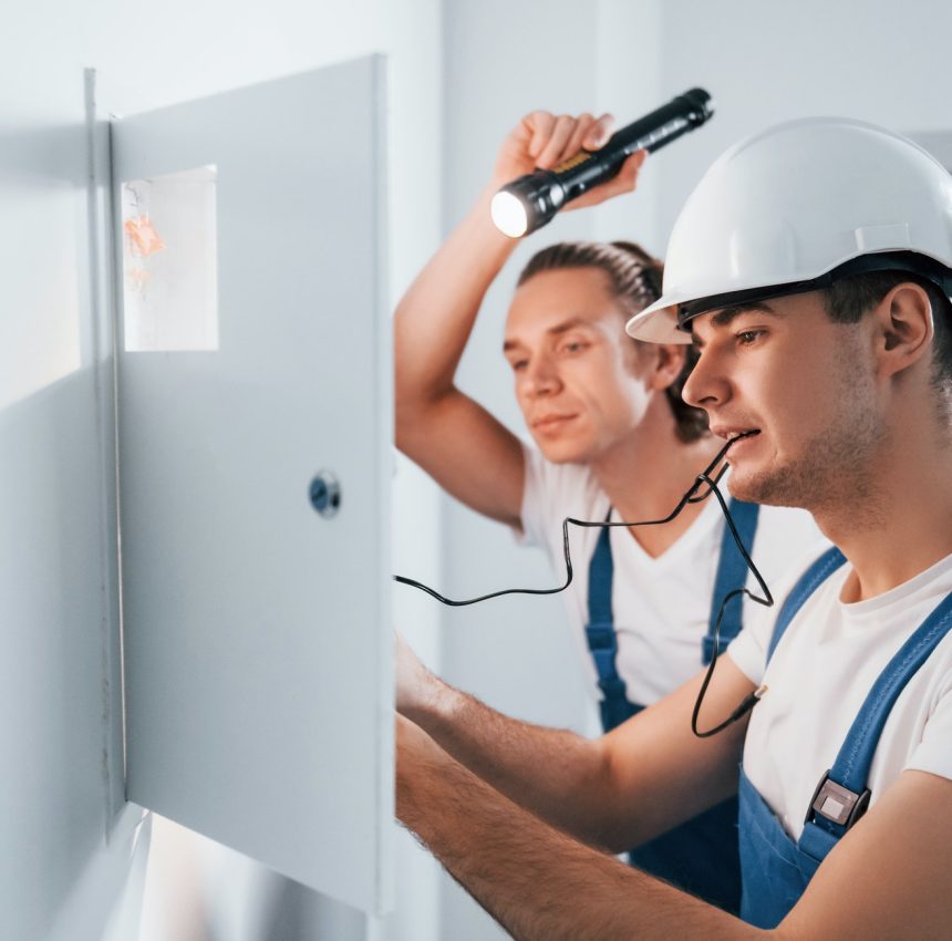 two-young-male-electricians-works-indoors-together-using-flashlight.jpg