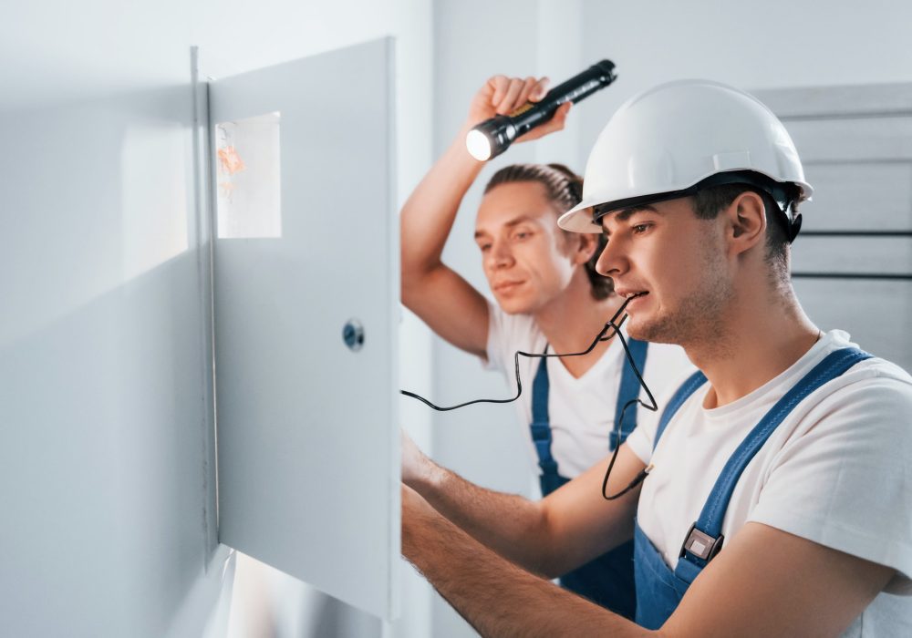 two-young-male-electricians-works-indoors-together-using-flashlight.jpg
